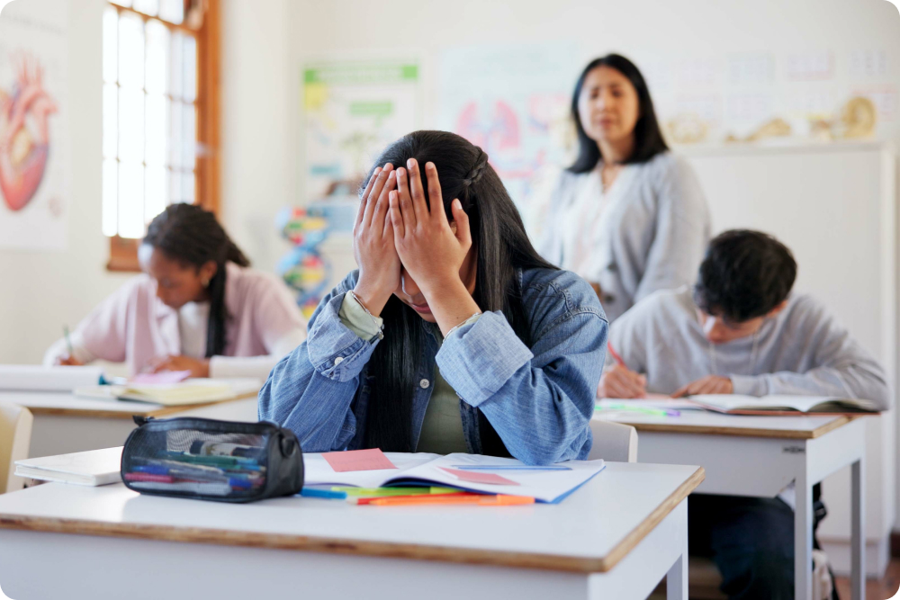 image showing a student at a desk looking overwhelmed with schoolwork